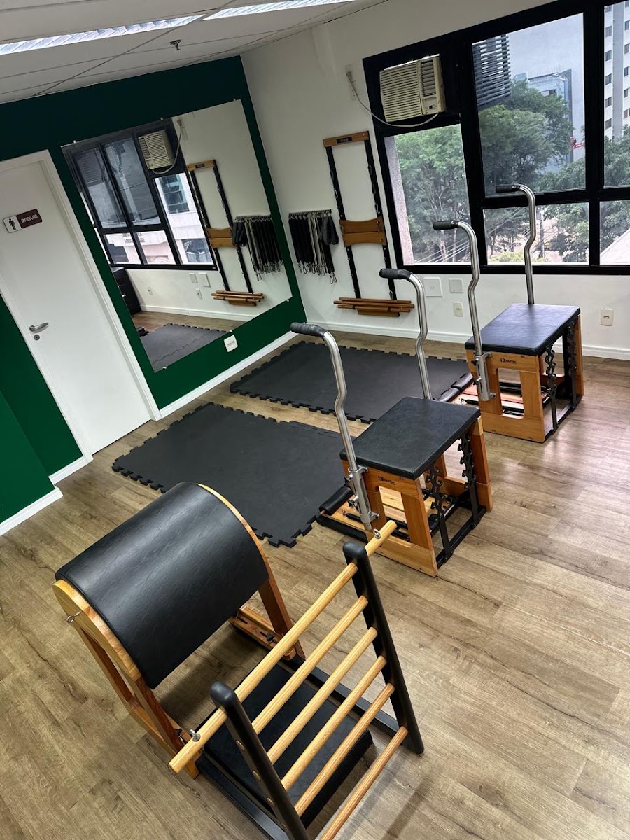Parede verde da clínica com tatames e aparelhos de pilates