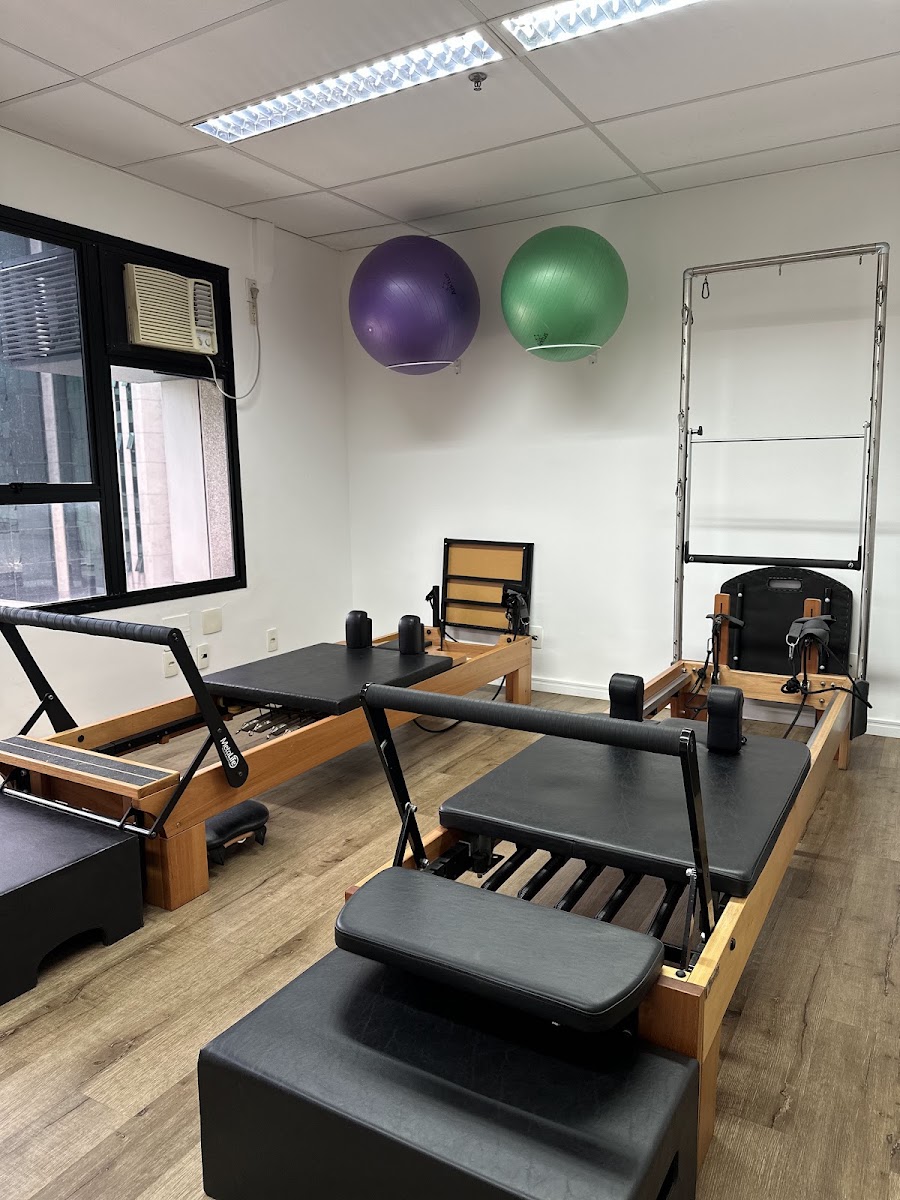 Reformers de madeira e bolas de pilates na parede