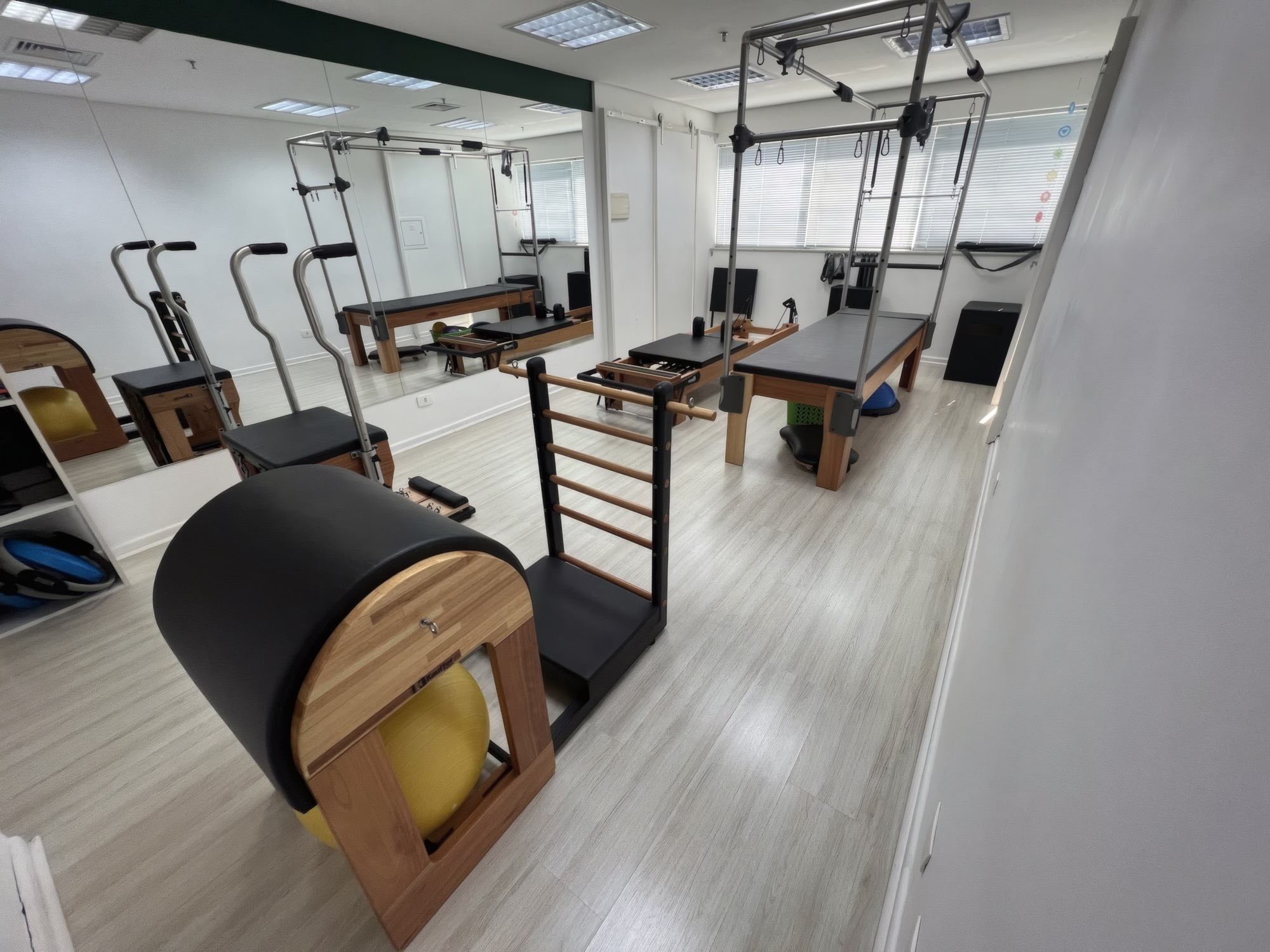 Estúdio da Clínica Eliane Karasawa com aparelhos de pilates em madeira: cadillac, reformer e barrel